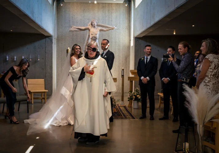 Priest and newlyweds are standing in the front of the altar during Calgary wedding