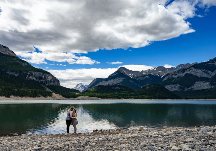 Same sex couple romantic kiss at Bow Lake. They Are surrounded by the Canadian Rockies.