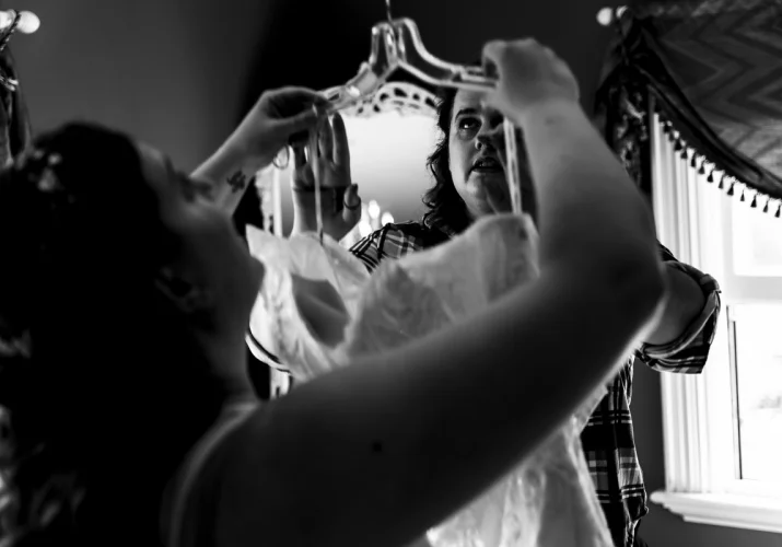 Bride is putting on a wedding dress before wedding ceremony in Calgary.
