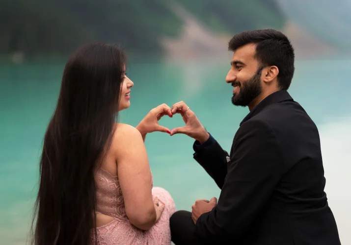 Couple in love look at each other and creates a hart with their hands.