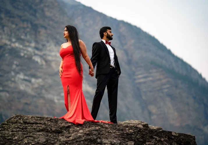 Couple of lovers holds their hands and look at majestic Canadian Rockies.