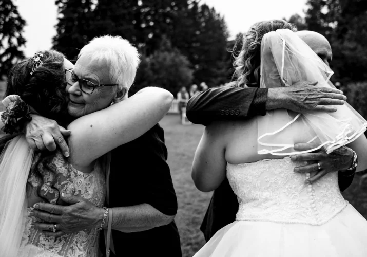 Parents of the newlyweds are hugging the brides.
