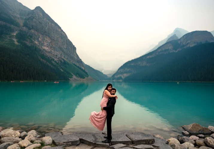 A man lifts his fiancee and they both look at Banff Weeding Photographer at Lake Louise