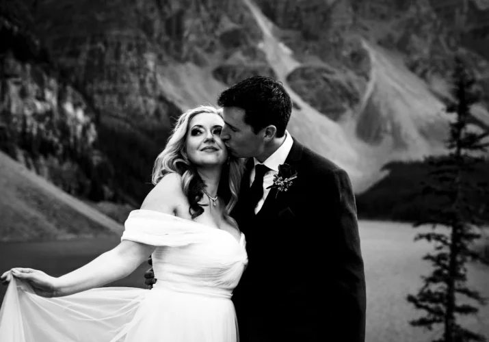 Groom kisses brides cheek.