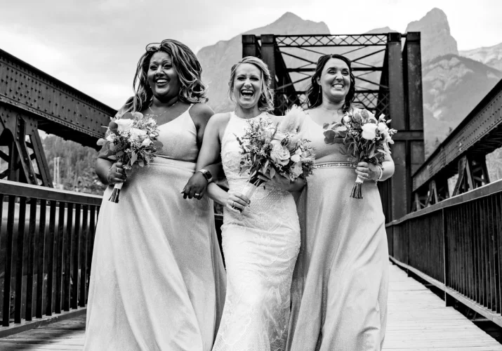 bride and bride maids walking and laughing on the bridge in Canmore.