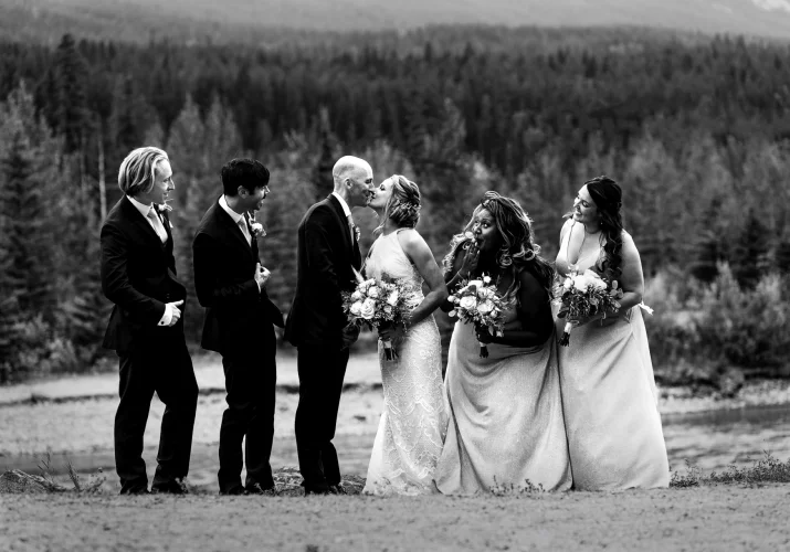 bride and groom are kissing during the bridal party