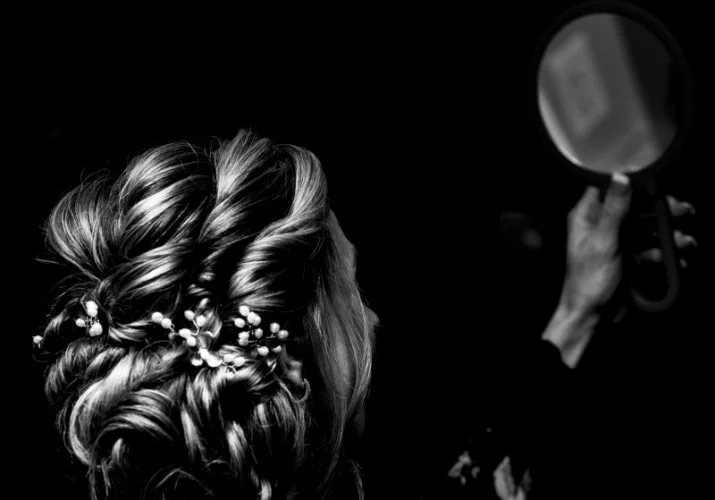 bride is looking at the mirror and checking her hair before the Wedding ceremony in Calgary