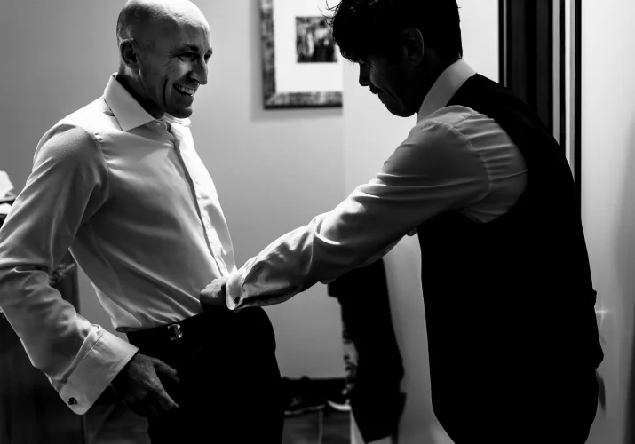 The best man helping the groom to zip his panties.