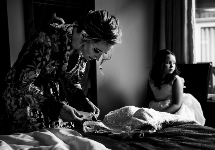 Bride is checking a wedding dress and flower girl is looking through the window.