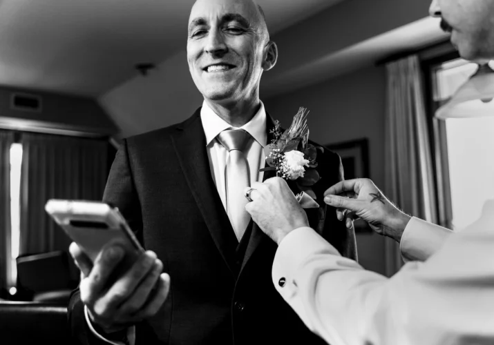 Groom looking at his cellphone and checking what time is it before Calgary wedding ceremony