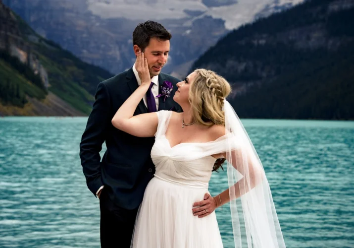 Bride puts her hand on the grooms cheek. They smile to each other.