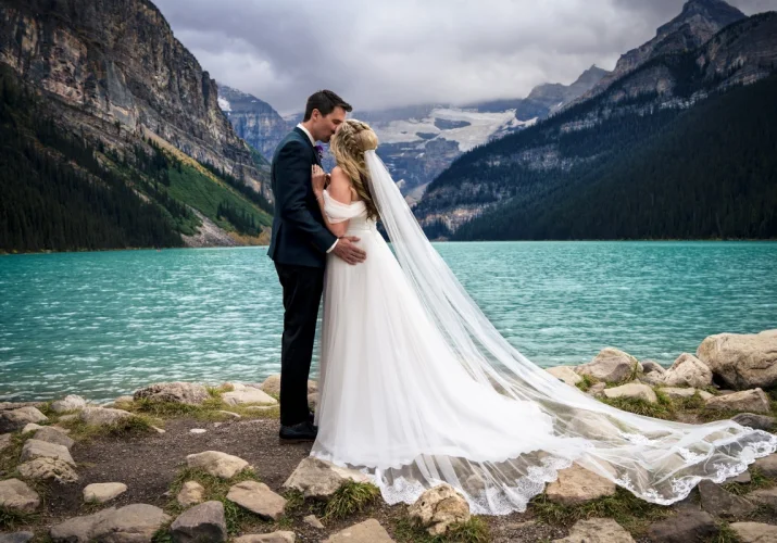 Banff Wedding Photography at Lake Louise. Newlyweds kiss at the lake.