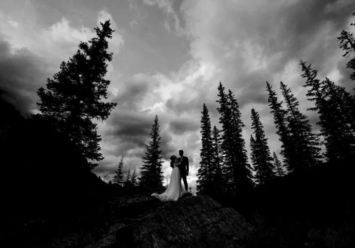 Banff Wedding Photography in dark and moody style. Newlyweds look at each other in the Canadian Rockies.