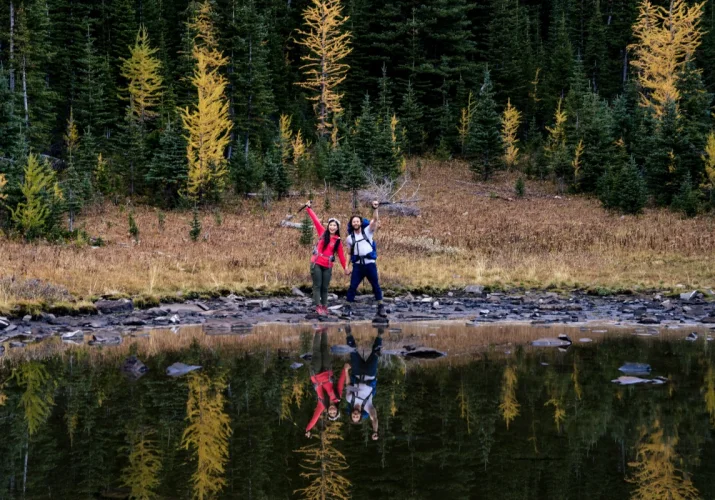 Hikers on their way lifting their equipment and smile to camera.
