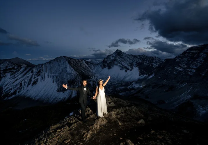 Wife and husband celebrate their love on the peak of the mountain in Banff.