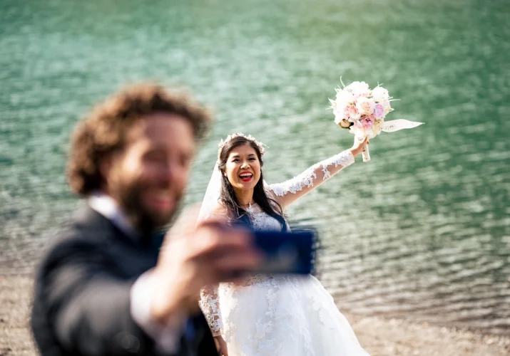 Groom is taking photos of the bride.