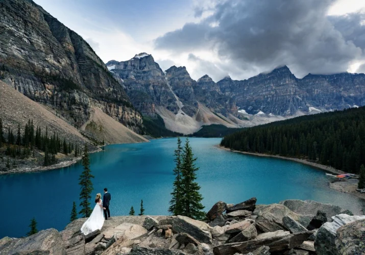 Bride and Groom adore tremendous mountains and blue Moraine Lake in Banff National Park.