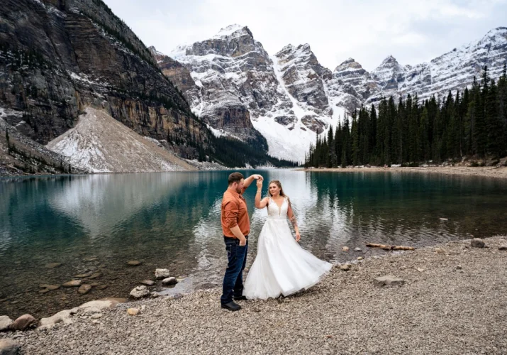 Bride and Groom are dancing at the Moraine Lake in Banff.