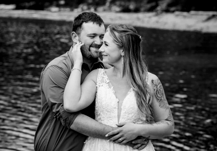 Groom whisper a secret into bride's ear. They both laugh.