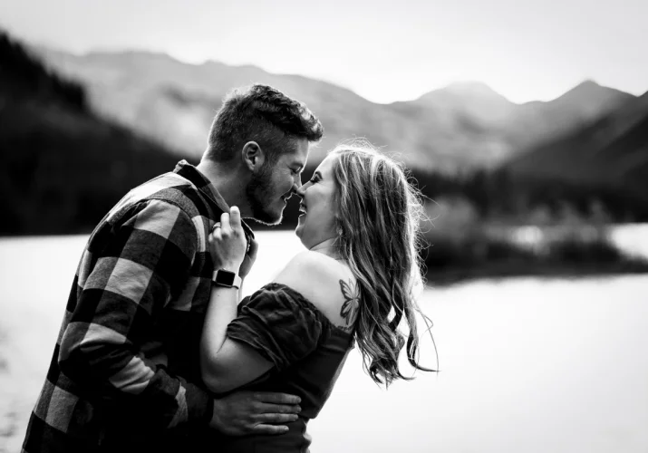 Happy freshly engaged couple give yourself chicken-kisses. They are touching their noses and laugh.
