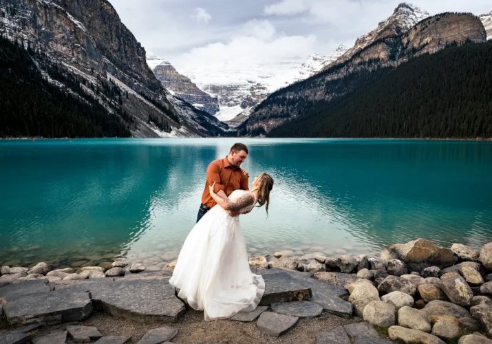 Happy newlyweds celebrate their love by dancing at Lake Louise. Lake Louise is turquoise and stunning.