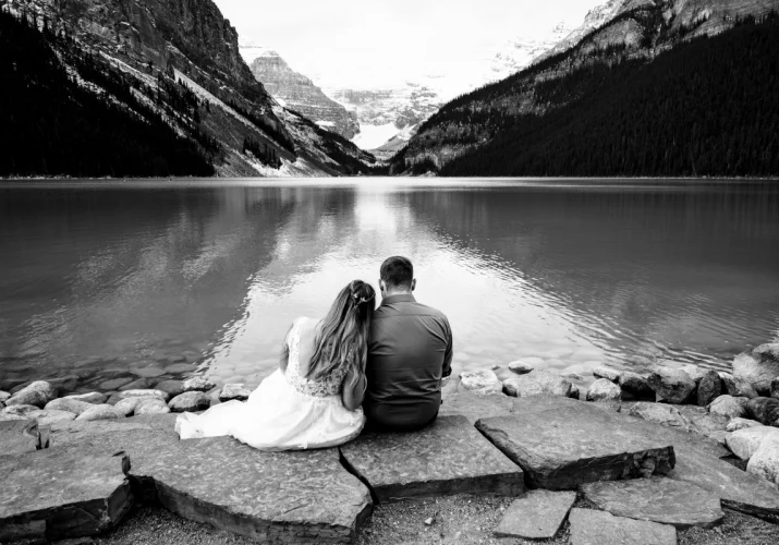 Groom and Bride sit at the stairs an enjoy unique Lake Louise in Banff.