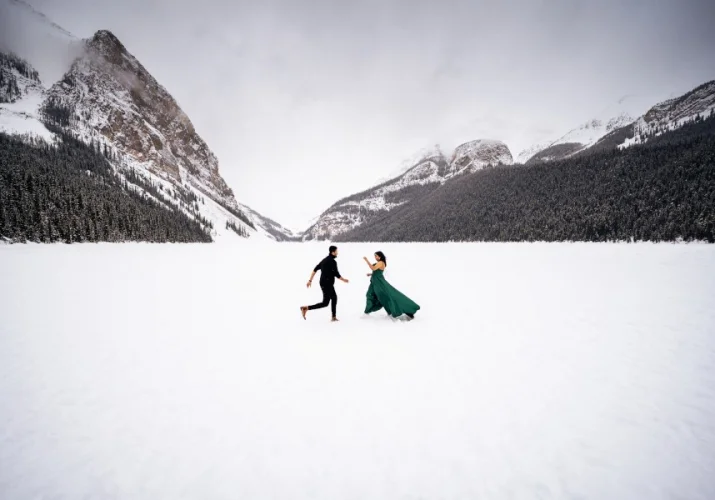 Couple dance in the middle of frozen Lake Louise. They are surrounded by gorgeous mountains.