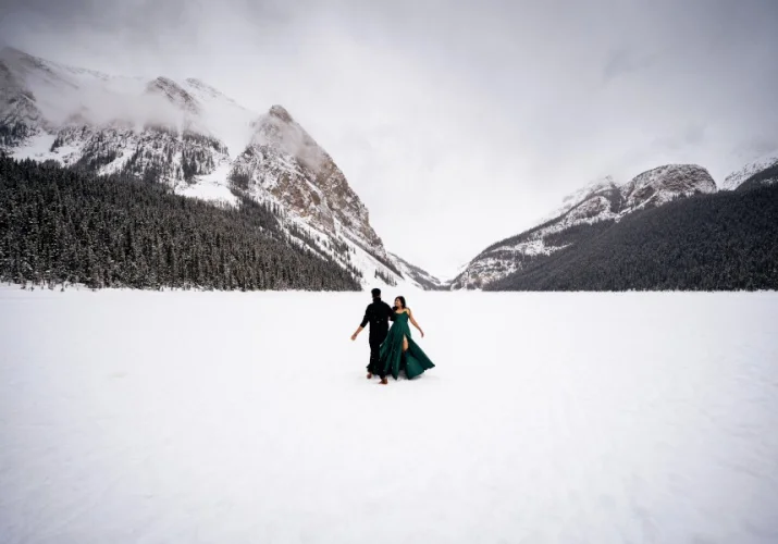 Indian couple dance on the Lake Louise. Lake and mountains are covered with fresh snow.