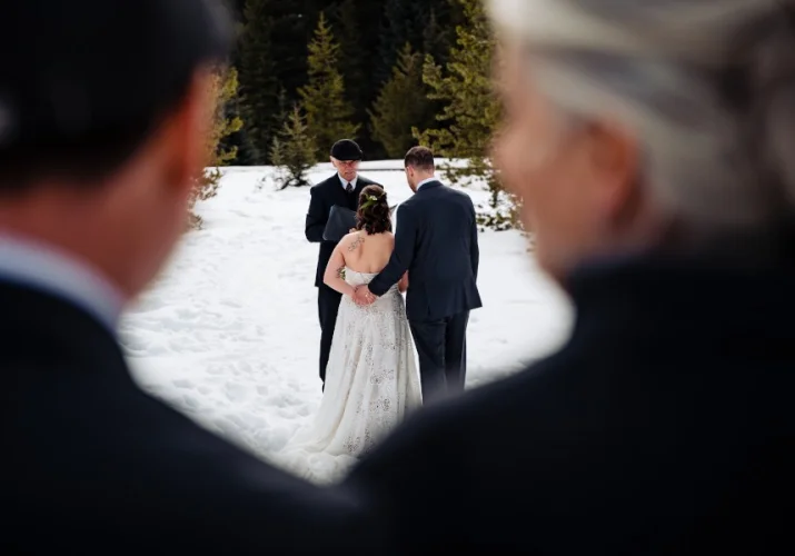 Bride and groom hold their hand during their intimate winter wedding in Banff.
