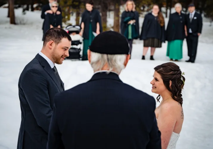 Intimate wedding in Banff. Commissioner gives a speech while bride and groom look at each other. Familly and friends at the background.