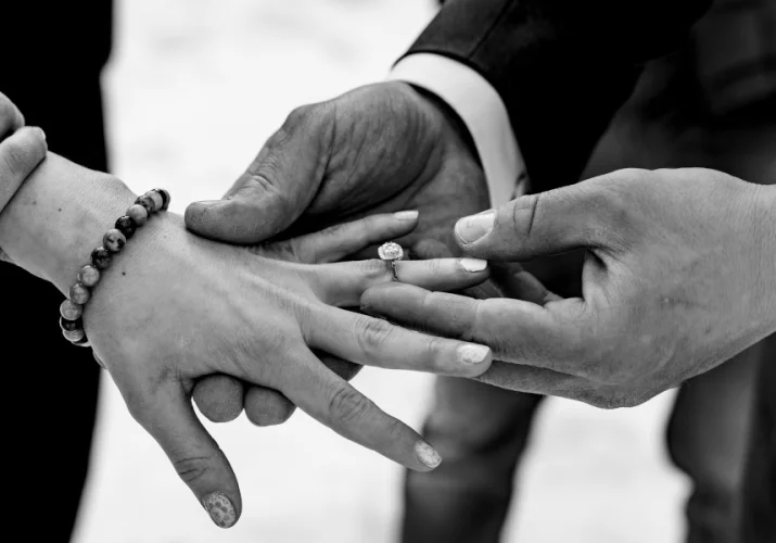 Groom puts wedding ring on the bride's hand.