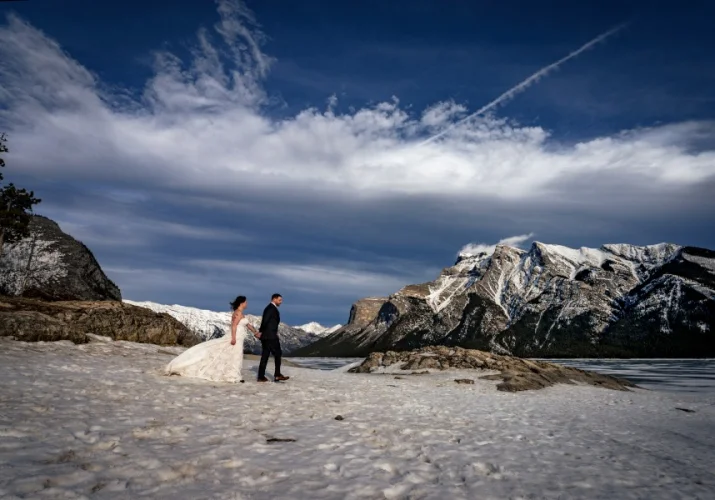 Newlyweds walk down the Minnewanka Lake.