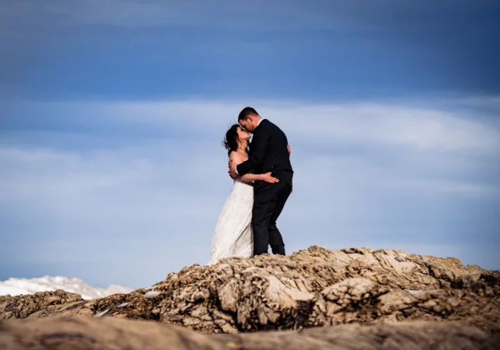 Newlyweds kissing at the giant rock in Banff.