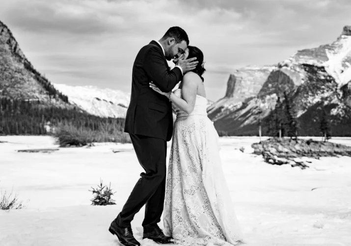 Black and white portrait in Banff National Park. Couple are kissing after their wedding.