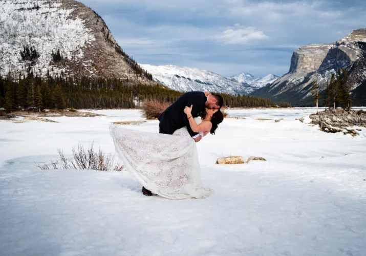 Newlyweds dance during winter wedding session in Banff. They are surrounded by the mountains.