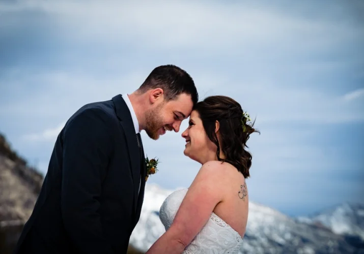 bride and groom touch their forehead and smile.