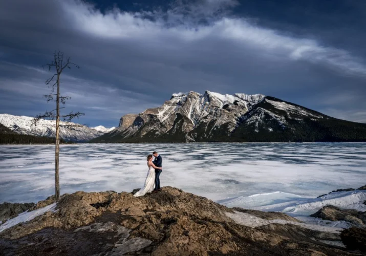 bride and groom hug during windy photo session in Banff.
