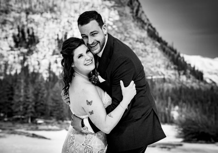 Bride and groom hug each other and smile to the camera.