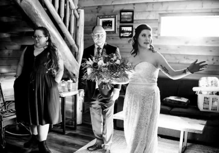 Bride's getting ready time in a cosy cabin in Banff. She points and shows at something behind a window.