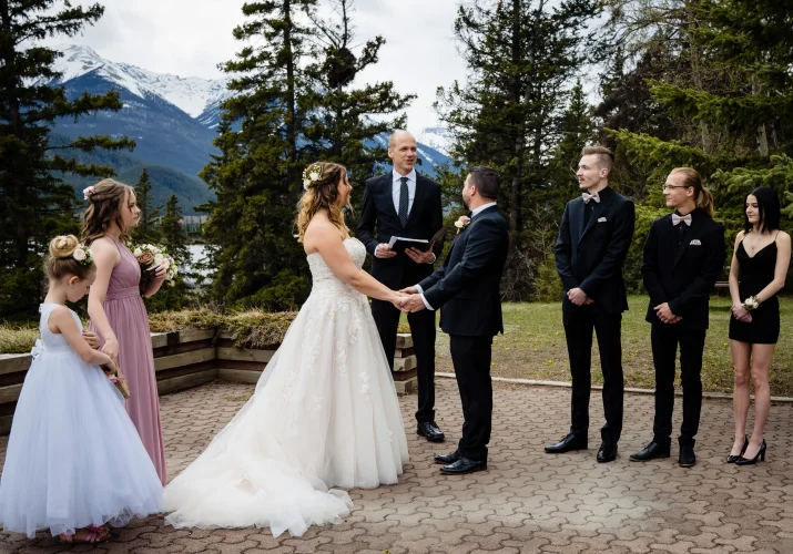 Officiant gives speech during Banff Wedding Ceremony. Bride and groom hold hands.