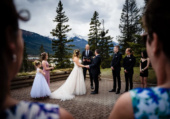 Banff Wedding Ceremony hold outside of Juniper hotel. Bride and groom look at each other while guests admire the ceremony.