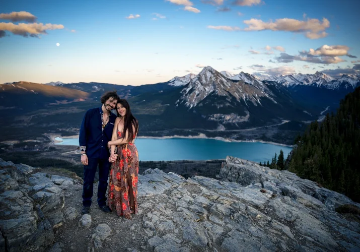 Banff Engagement Photography on the top of the mountain with a couple holding their hands and at Banff Wedding Photographer camera.