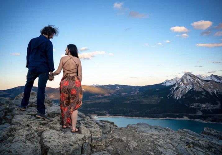 Engaged couple admire a view of Canadian Rockies.