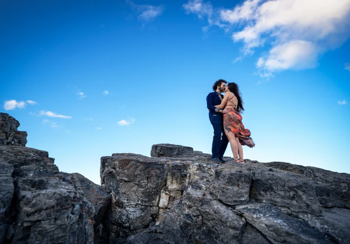 Banff Engagement Photographer created this unique photo of couple in love standing on giant rock in the Canadian Rocky Mountains.