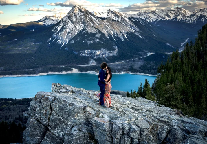 Couple in love huh each other on the top of the mountain against a background of giant mountains and blue lake.