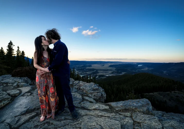 Engaged couple share a kiss during mountain session captured by Calgary Wedding Photographer