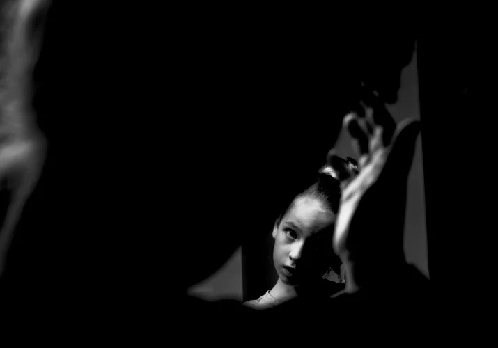 black and white photo of flower girl fixing her hair in the mirror