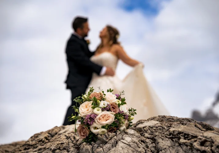 bouquet of flowers. On the background kissing newlyweds