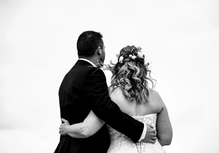 Bride and groom standing back to camera .