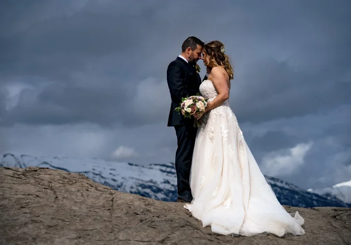 Bride and groom's portrait in the Canadian Mountains. They touches their foreheads.